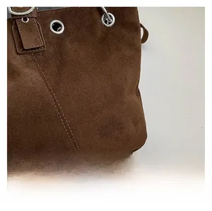 Macro shot of brown suede texture with neat stitching and silver metal eyelets on a tote bag