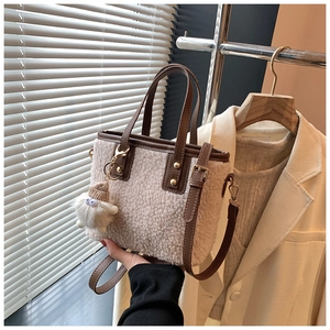 Detail of teddy plush bucket bag with brown leather trim and cute mascot charm