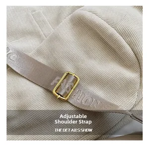 Dettaglio della tracolla tessuta regolabile con fibbia dorata su borsa a bauletto in velluto