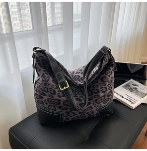 Detail of leopard print tote bag with black leather trim and white contrast stitching