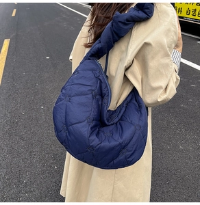 Detail view of navy blue quilted dumpling bag with heart embroidery and ruched strap