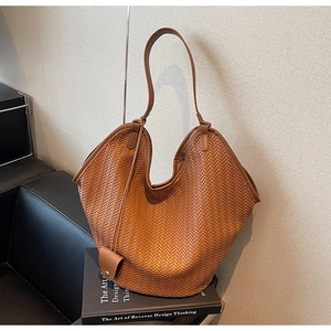 Close-up of brown woven tote bag showing detailed herringbone texture on leather surface
