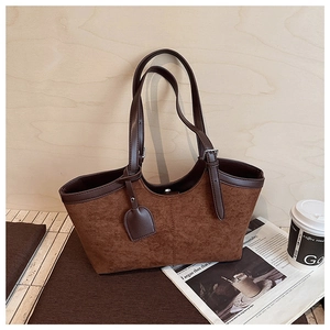 Detail of suede and leather tote bag with magnetic closure on a wooden background