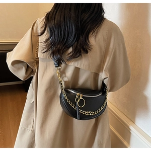 Détail du sac selle noir en cuir avec chaîne dorée et double fermeture éclair à anneaux