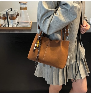 Detailed macro view of dark brown leather handbag featuring a folk-style wooden bead charm