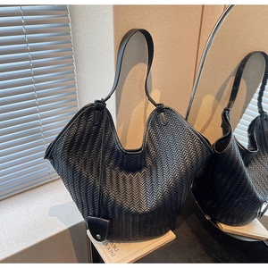 Macro detail of black woven tote bag with herringbone texture and single shoulder strap