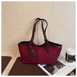 Macro detail of wine red suede tote bag with brown leather handles and smooth trim