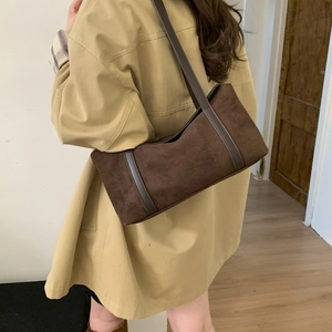 Detailed close-up of dark brown suede pillow bag with vertical leather trim accents
