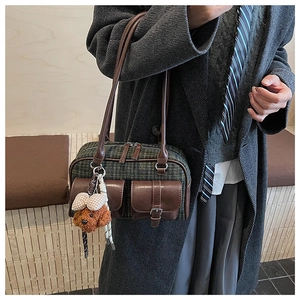 Détail du sac rétro à carreaux verts avec poches en cuir et pendentif d'ours en peluche