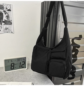 Détail du sac bandoulière en toile noire avec poches multiples fonctionnelles de style utilitaire