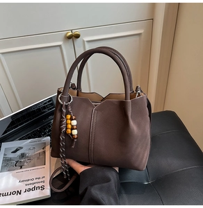Detail of dark brown bucket bag with beaded tassel and smooth matte texture finish