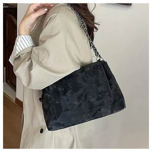 Détail du sac à bandoulière matelassé noir avec texture huilée vintage et chaîne argentée