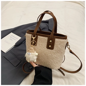 Detail of plush fleece bucket bag with brown leather trim and cute monster charm
