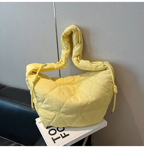 Close-up of yellow hobo bag featuring heart-shaped quilting and wide shoulder strap