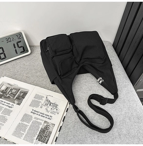 Détail du sac bandoulière en toile noire avec plusieurs poches et fermetures éclair en métal