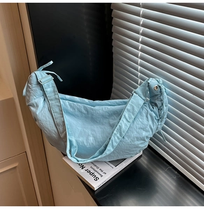 Detail of light blue pleated nylon crescent bag showing textured fabric and wide strap