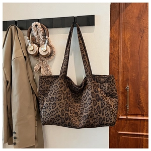 Detail of leopard print tote bag hanging with autumn coat and plush headphones