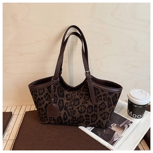 Close-up of leopard print suede tote bag with brown leather handles and tag detail
