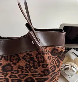 Close-up of leopard print tote bag with brown leather trim and metallic rivet details