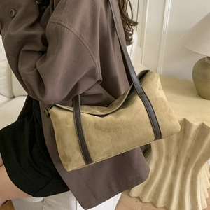 Close-up of retro mustard green suede shoulder bag with brown leather strap in home setting