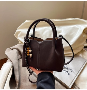Detail of dark brown tote bag with wood bead tassel and textured leather finish