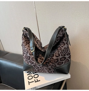 Detail of leopard print tote bag featuring black leather trim and gold hardware accents