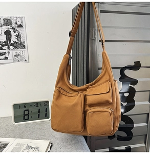 Gros plan d'un sac bandoulière en toile fauve avec plusieurs poches et sangle réglable