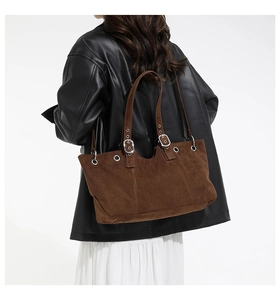 Detailed macro view of dark brown suede leather texture and silver buckle accents on tote bag