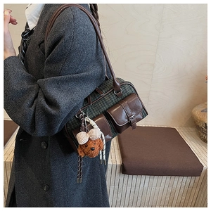 Close-up of vintage plaid Boston bag with leather accents and teddy bear charm accessory