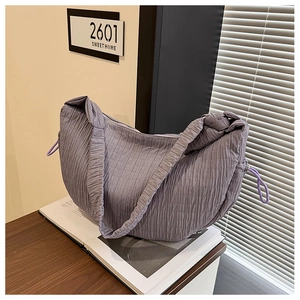 Detail view of purple pleated hobo bag texture and decorative drawstring on wooden table