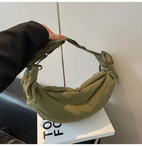Detail of olive green crescent dumpling bag in textured nylon with wide shoulder strap