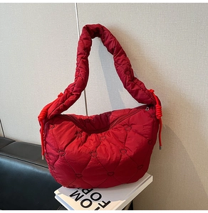 Detail of red heart-shaped quilted puff shoulder bag with plush nylon texture