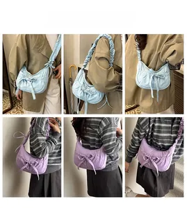 Vue détaillée des bretelles plissées et nœuds sur des sacs bandoulière demi-lune souples