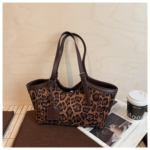 Detail of leopard print tote bag with brown leather handles and vintage metal buckle