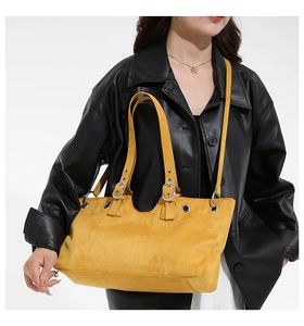 Detail of yellow suede tote bag featuring silver adjustable buckles and metal grommets