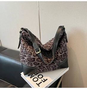 Detailed view of leopard print tote with black leather trim and gold adjustable buckle