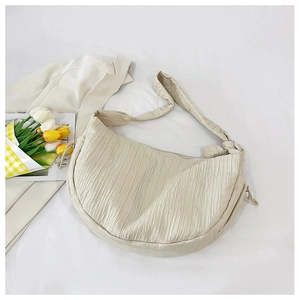 Macro detail of creamy white pleated fabric and texture on the crescent tote bag