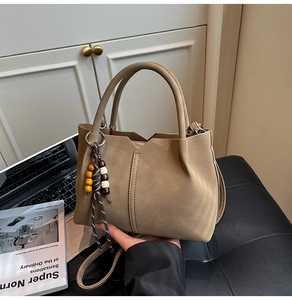Detail of khaki pebbled leather tote with wooden bead tassel and zip closure