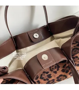 Detail view of the magnetic snap closure on a leopard print textured tote bag