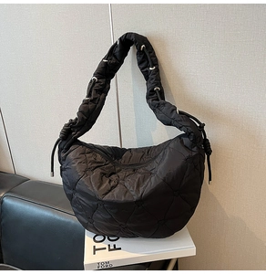 Detail of black quilted dumpling bag featuring heart patterns and ruffled shoulder strap