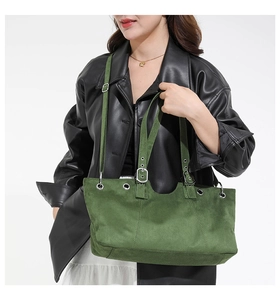 Detail view of green suede tote bag featuring silver metal eyelets and adjustable straps