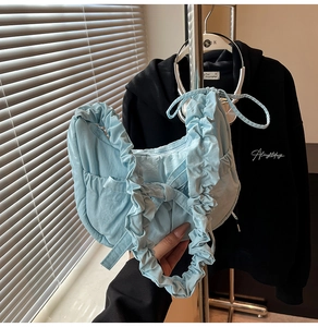 Détail du sac croissant plissé bleu clair avec nœud décoratif et large bandoulière