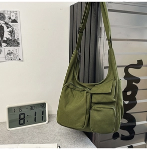 Gros plan d'un sac messager en toile vert foncé avec plusieurs poches fonctionnelles