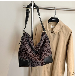 Detail of leopard print tote bag featuring leather trim and white contrast stitching