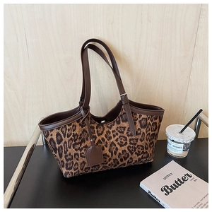 Detail of leopard print tote bag with brown leather handles and matching tassel charm
