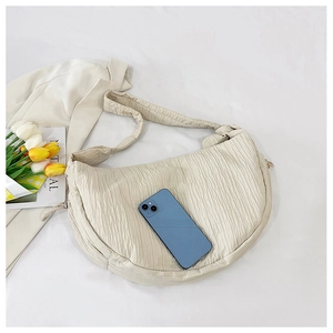 Close-up of cream pleated hobo bag showing size capacity with a smartphone