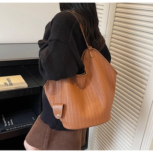 Gros plan sur un sac cabas tressé marron montrant la texture cuir et le motif chevron