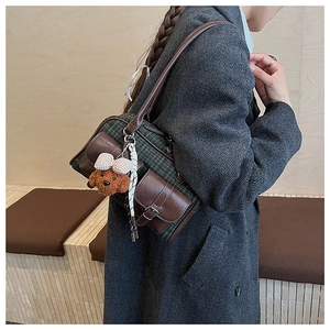 Détail du sac oreiller à carreaux vintage avec pendentif ours et accents en cuir
