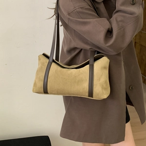 Close-up of a vintage mustard suede shoulder bag with dark brown leather straps on model