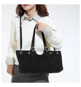 Detail view of black suede tote bag showing silver metal eyelets and adjustable strap